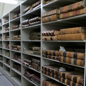 A storage room with shelves of large antique books.