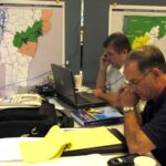 People at a cluttered desk on phones