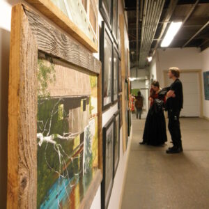 A man and woman viewing art in a gallery, a painting close in the foreground