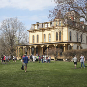 Crowd gather outside a mansion in early spring